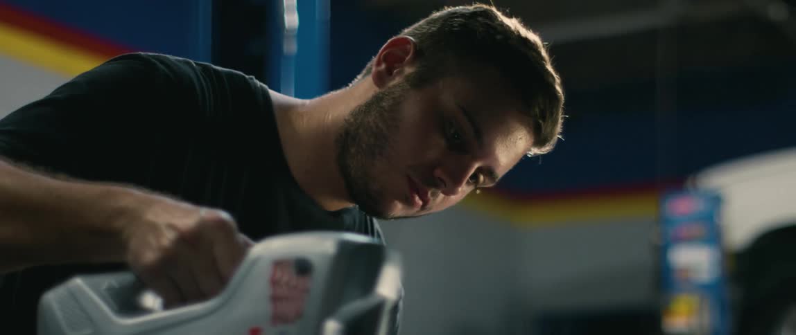 Young mechanic pouring oil into a vehicle inside an auto shop