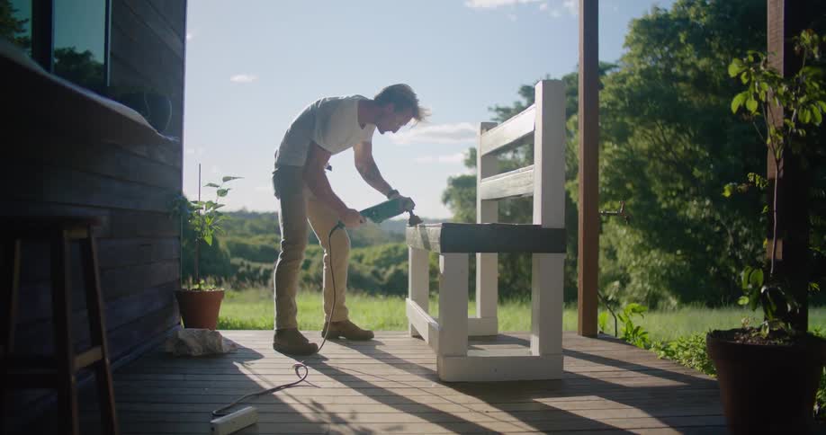 Man sands bench working on porch of home in countryside