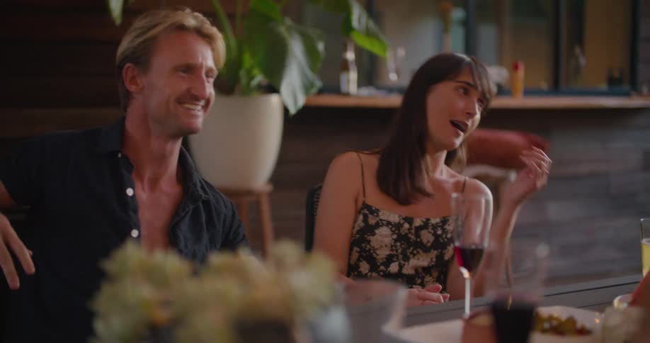 Young couple sitting at a table in a restaurant talking to friends