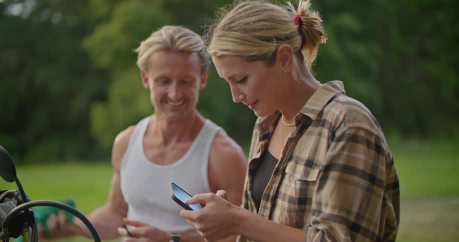 A woman is showing a man her cell phone outside