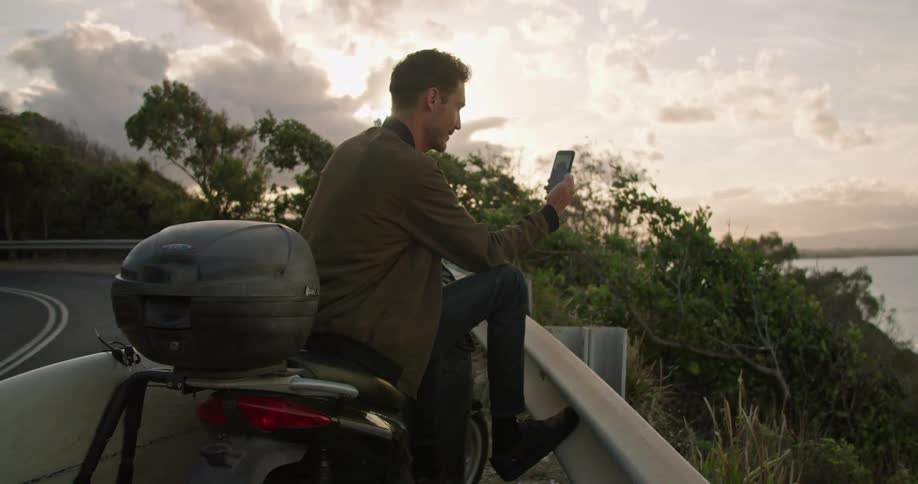 A man talks on his cell phone on video chat by the water