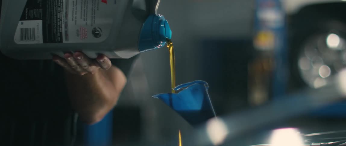 A mechanic is pouring fluid into a funnel