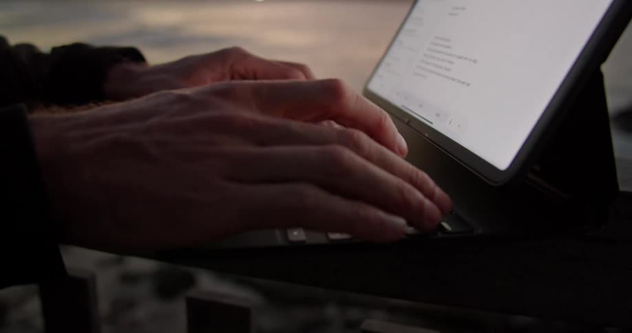 A person typing on a tablet outdoors