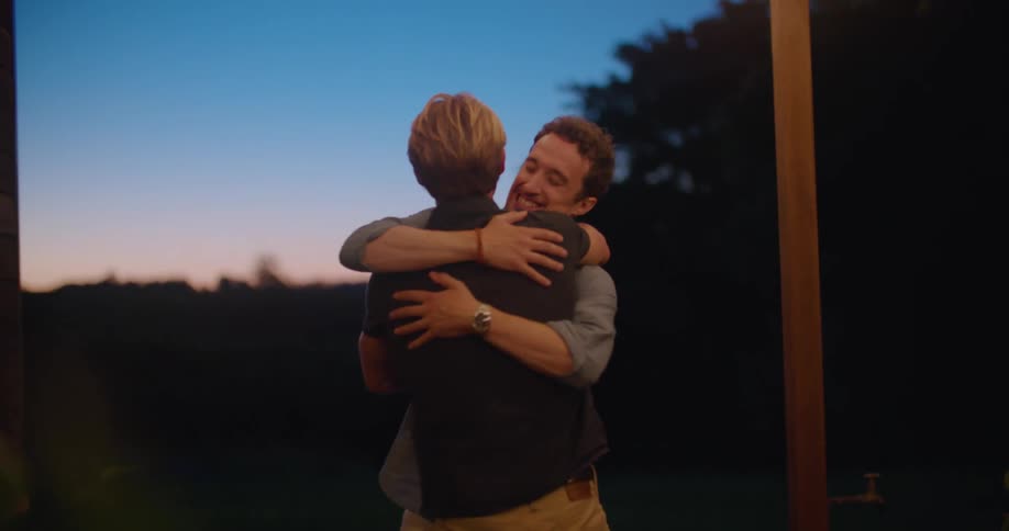Happy friends greet each other with a hug on the porch at sunset