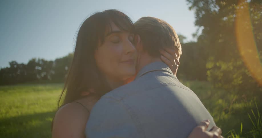 A man and woman hug outside on a sunny day