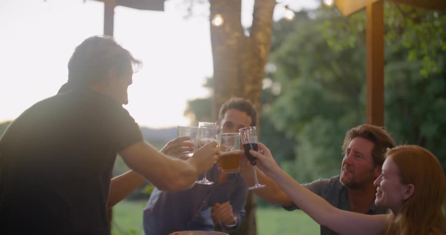 Group of friends toasting with wine on a table in the porch at sunset