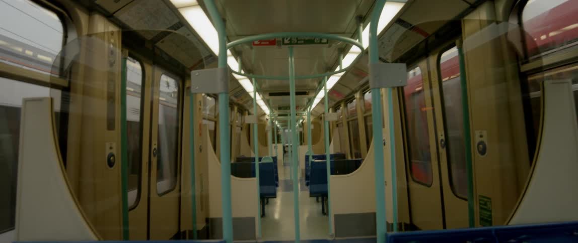 The inside of a commuter train as it travels past buildings and other trains