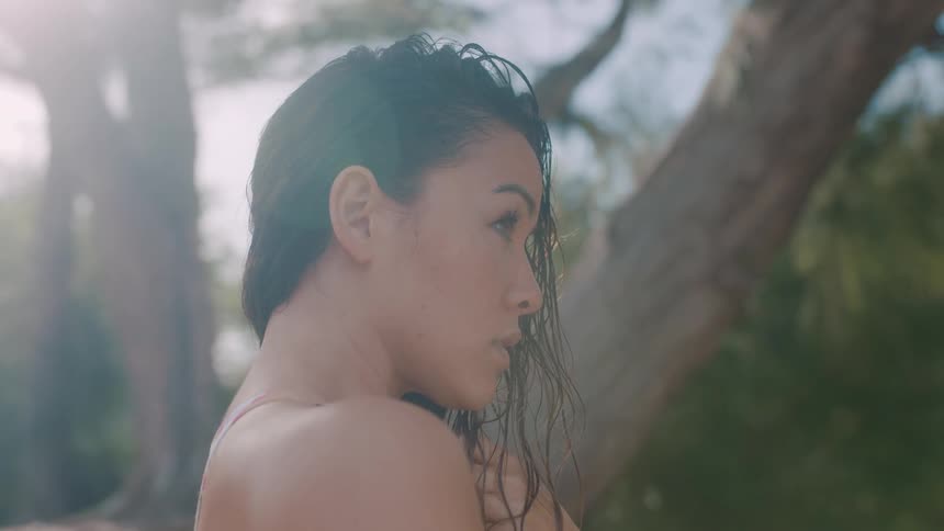 Woman wearing outfit with spaghetti straps poses outdoors near tree