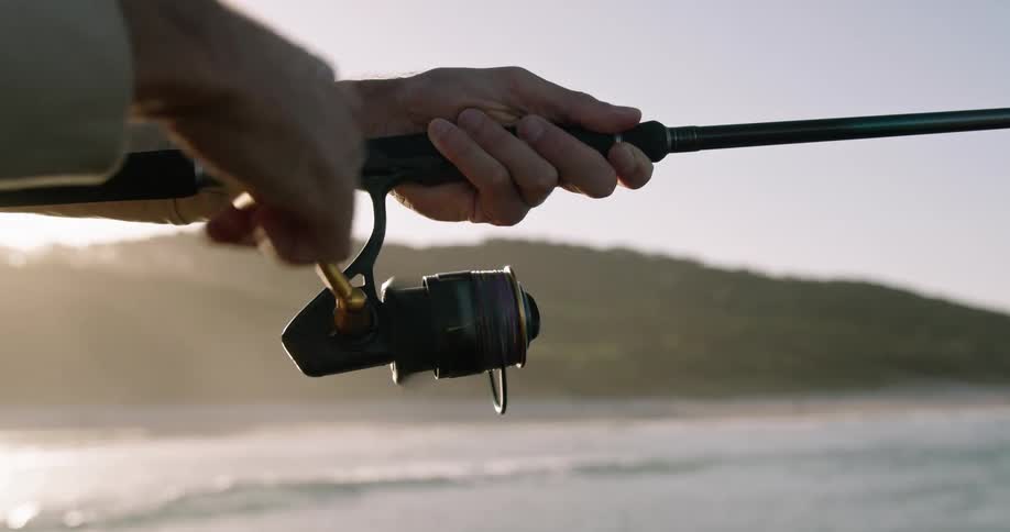 A man is fishing and reeling in his line