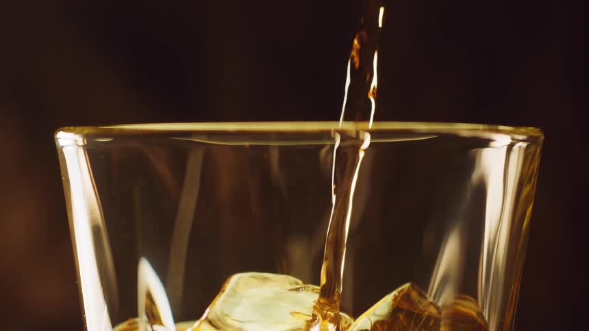 Golden liquor being poured on top of ice