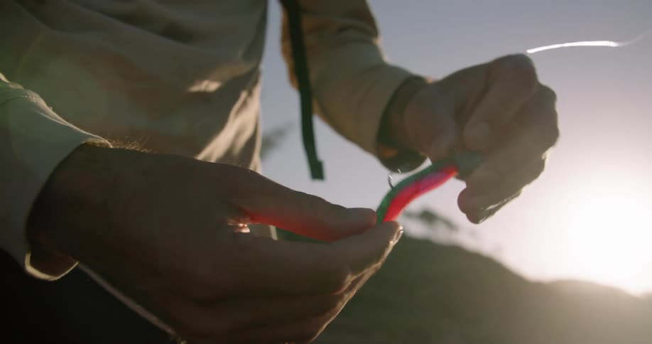 Someone is putting a minnow on a fishing hook