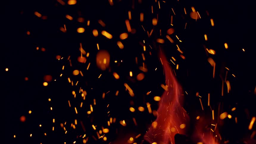 Fiery-orange flames on a campfire shooting red embers at night