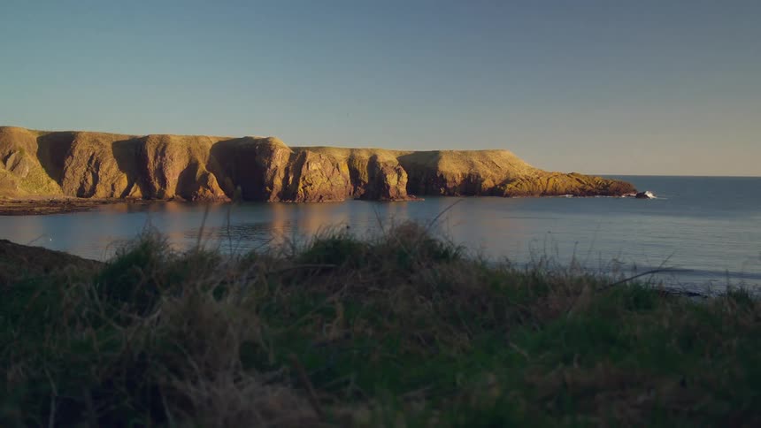 Coastal cliffs near the coast in the ocean at sunset