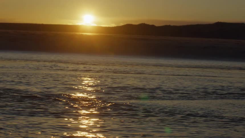 The ocean water is moving fast at sunset
