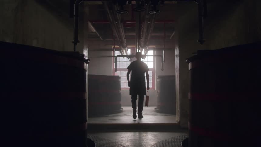 Silhouette of a distiller walking on the dimly lit hallway inside a distillery