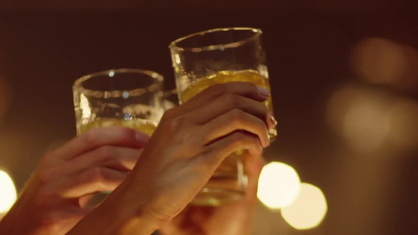 Three friends toast using amber liquor in short wide glasses
