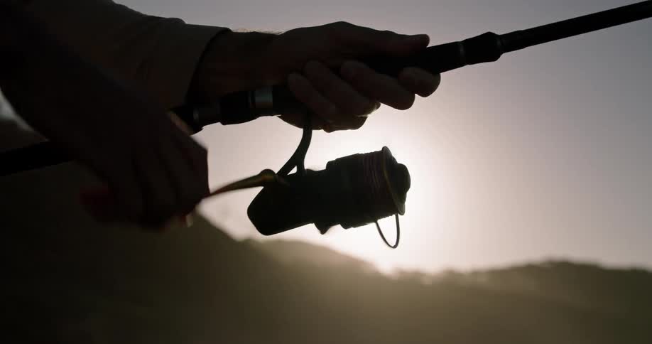 A man turns the reel on a fishing pole