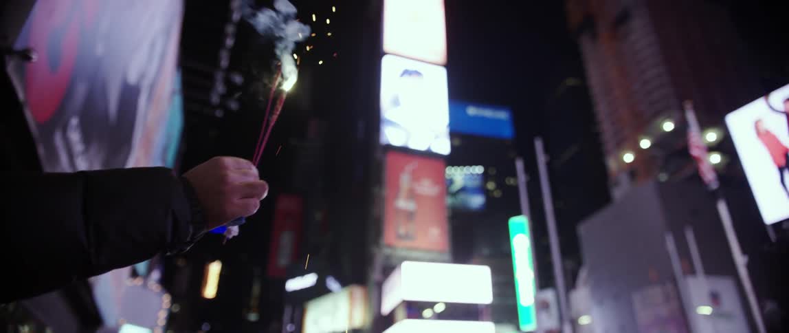 A person holds a sparkler in a city