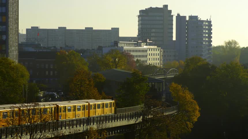 Yellow trains riding on elevated tracks through the city at sunset