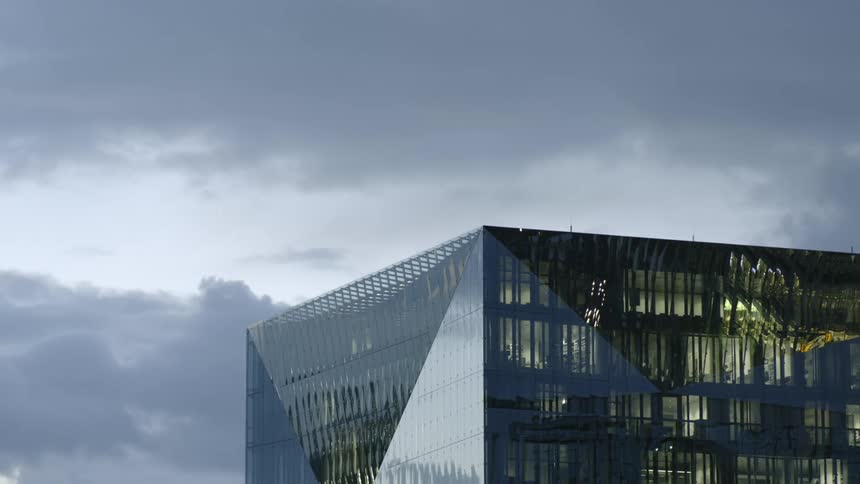 Glass facade of an office building under the cloudy sky