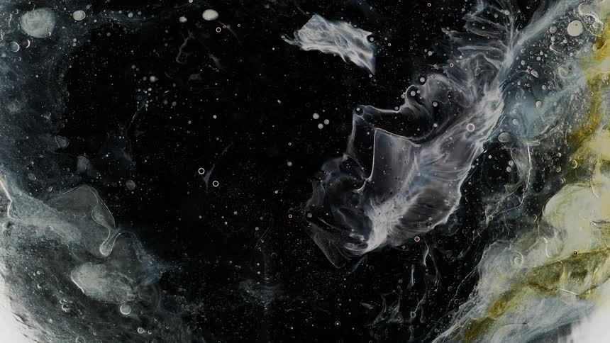 Flowing moving color liquid ink floating in water against a black background
