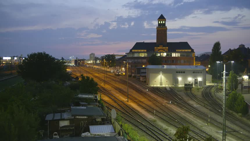 A series of train tracks outside of a train station at sunset