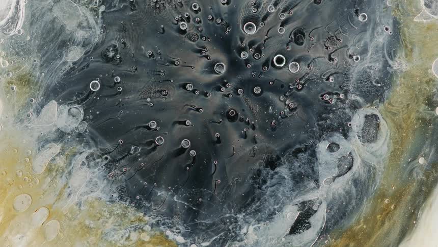 Liquidwith bubbles sprays out rapidly before flowing back toward center