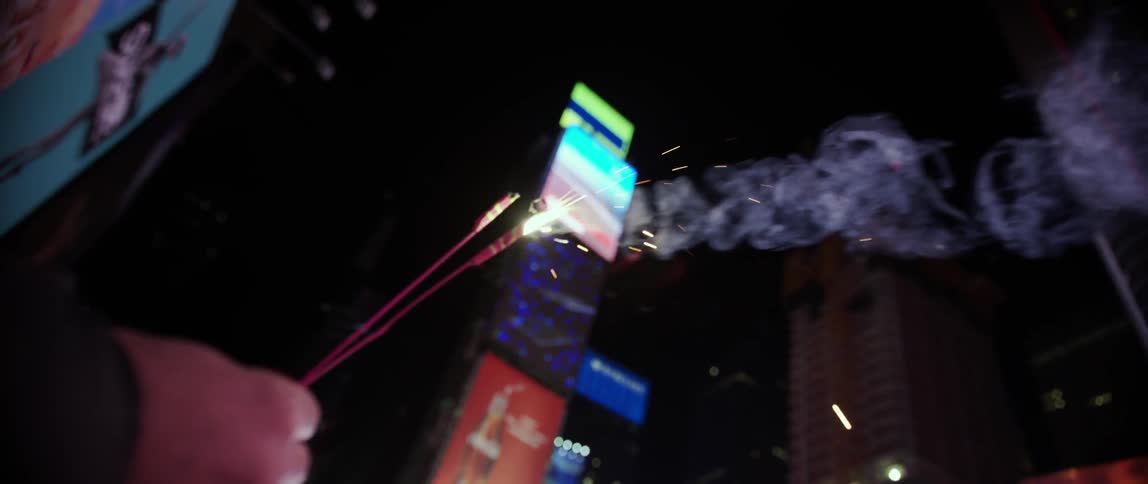 A persons hand holding fireworks in times square
