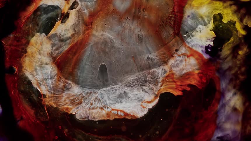 Colorful red flowing yellow liquid white ink floating in water against a black background