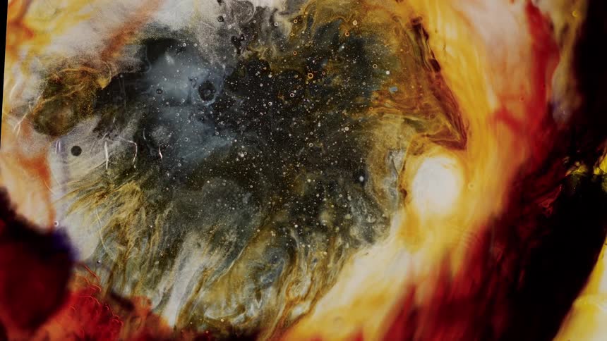 Red liquid bright yellow ink black flowing on water against a black background
