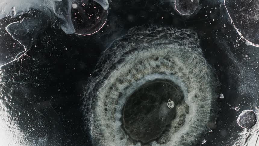 Abstract footage of bubbles in liquid as it mixes together