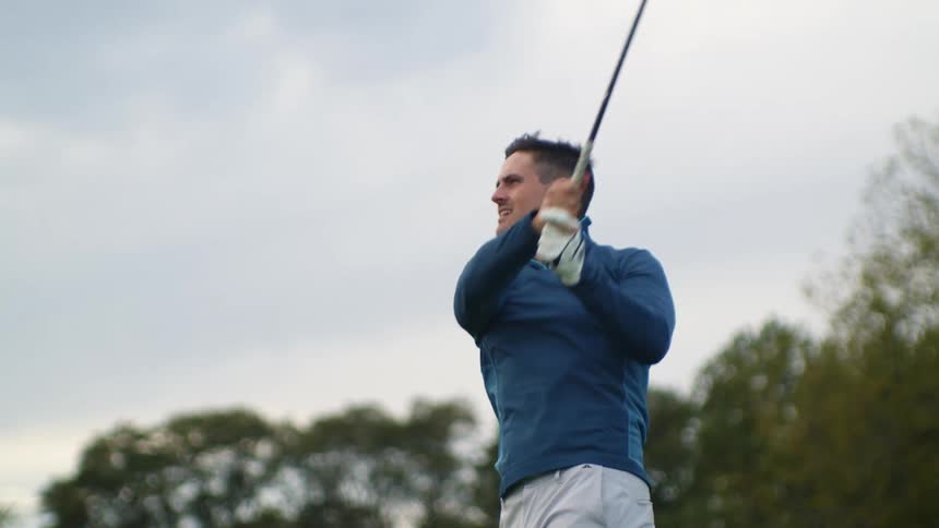 Man with blue shirt and and pants plays golf on golf course