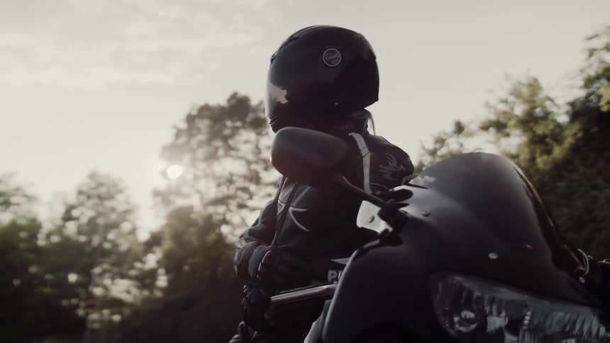 A person in black is leaning against a motorcycle