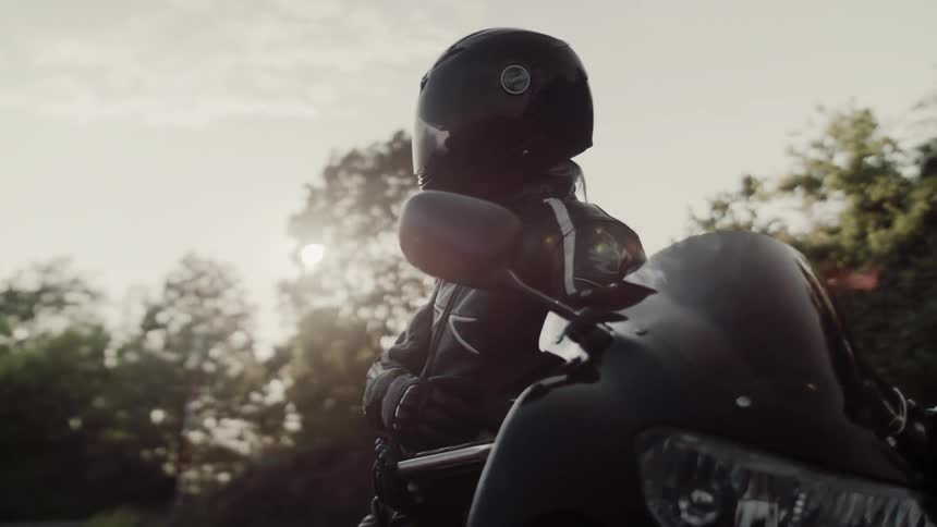 A man wearing a helmet is leaning on a motorcycle