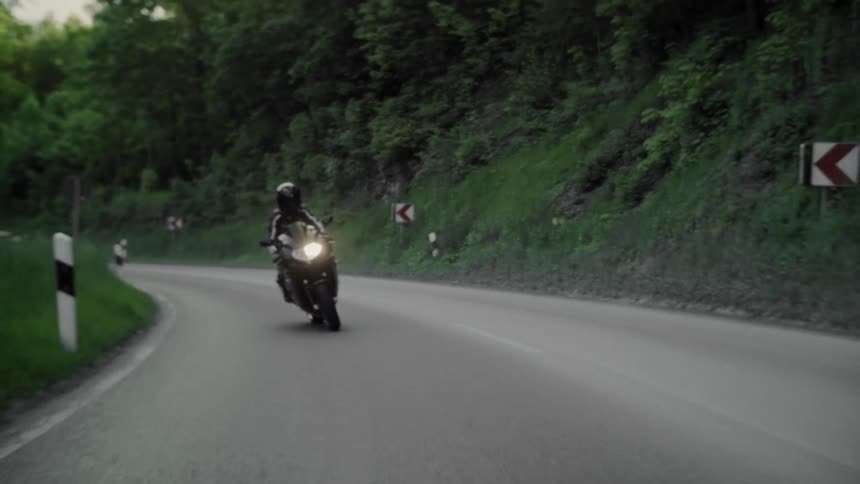 A motorcycle rides down a winding road