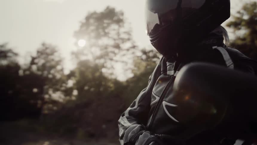 A person wearing a helmet leans on his motorcycle