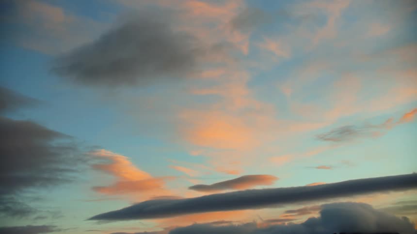 Blue sky and white clouds above dark gray storm clouds