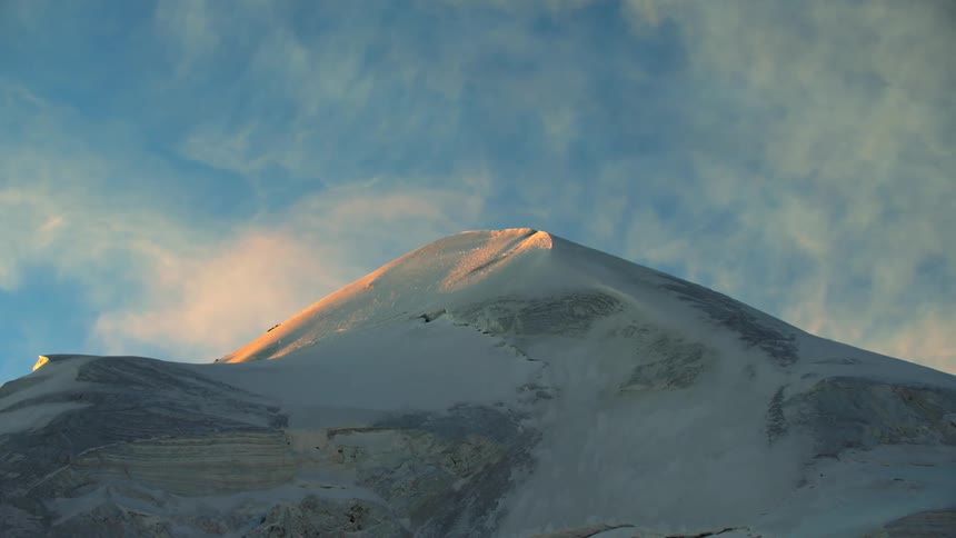 A snowy mountain peak under a blue daytime sky