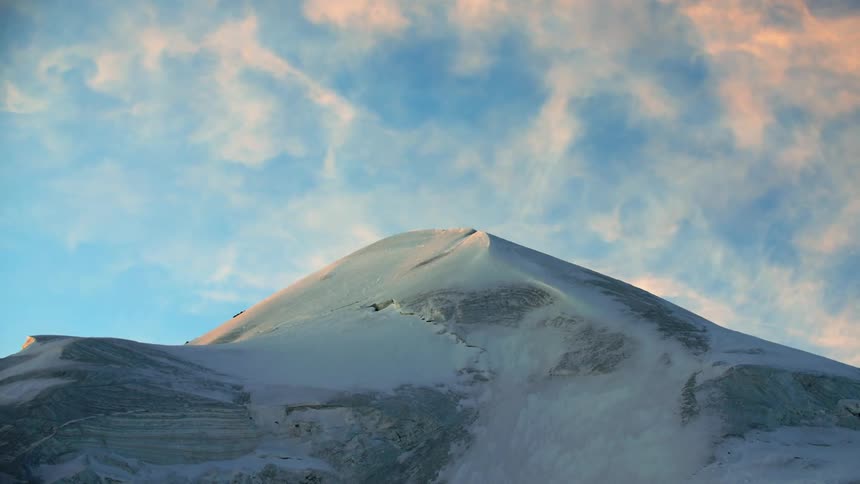 A view looking up toward the summit of an icy mountain in the evening