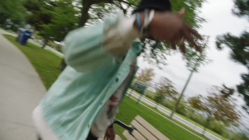 A teenage boy does a hand stand on a bench and then jumps down and high fives a girl that walks up to him
