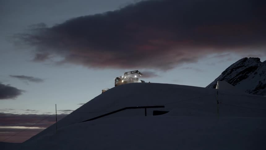 A view of machinery moving over a snowy hill