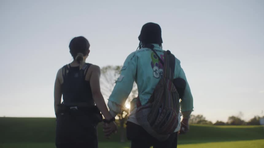 A boyfriend and girlfriend walking outdoors holding hands