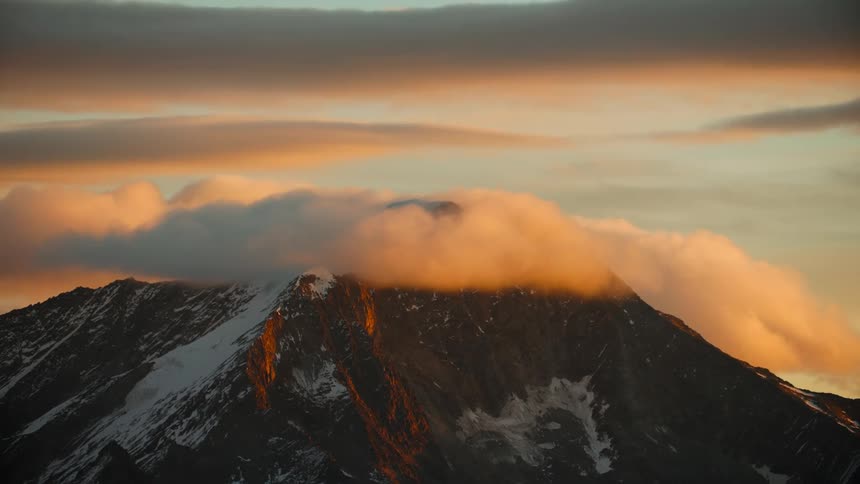A view of a mountain with clouds around it