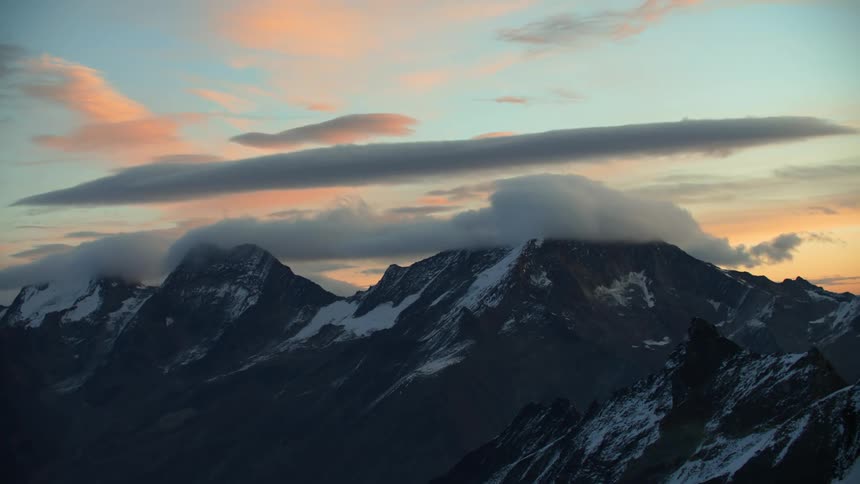 Snow covered mountains high in a cloudy sky