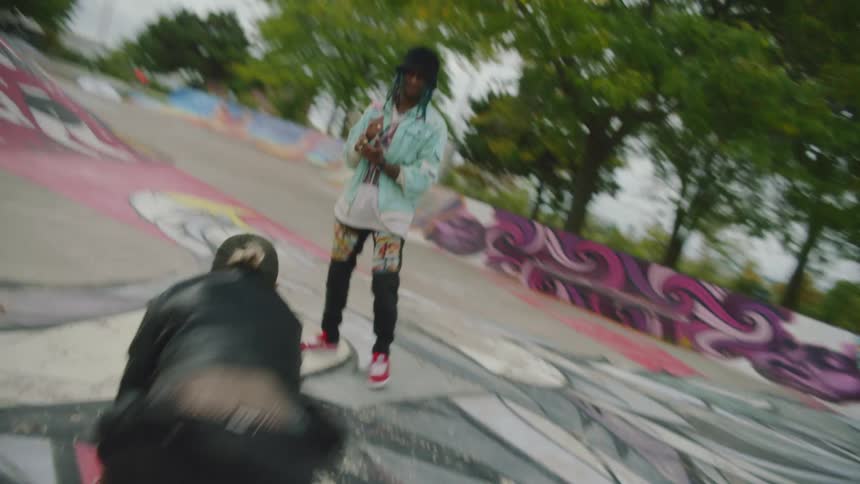A man and woman break dance in a graffiti covered skate park