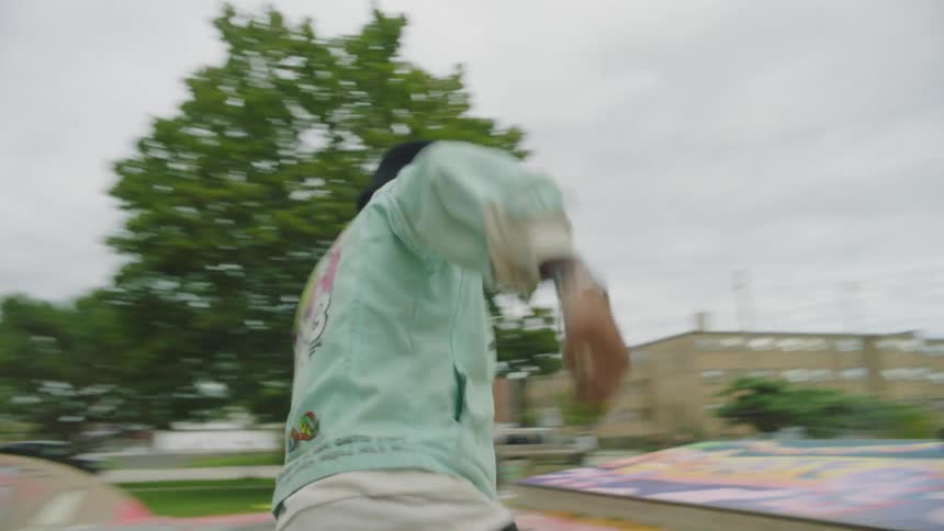 A woman is bending over watching a man dance in a park