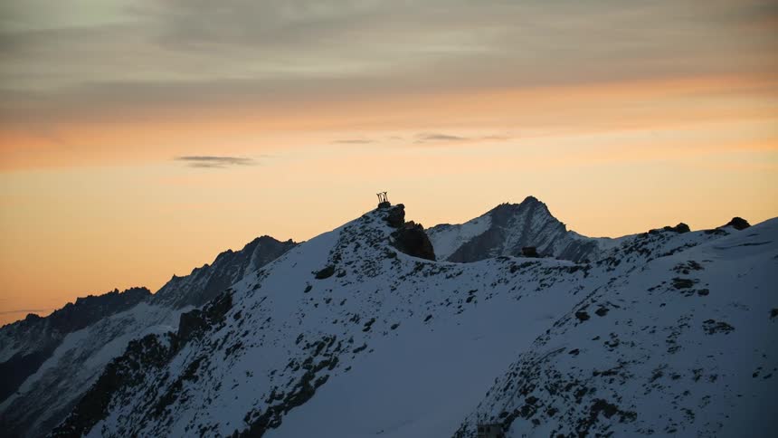 A view of a mountain covered in snow at sunset