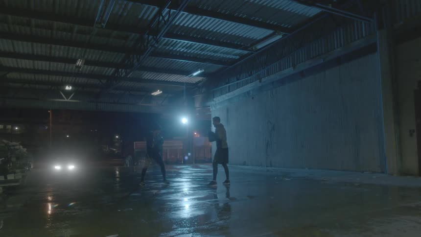 Two men do boxing training in building at night