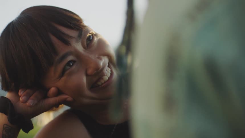 A woman smiles as she lies in the grass staring at her boyfriend