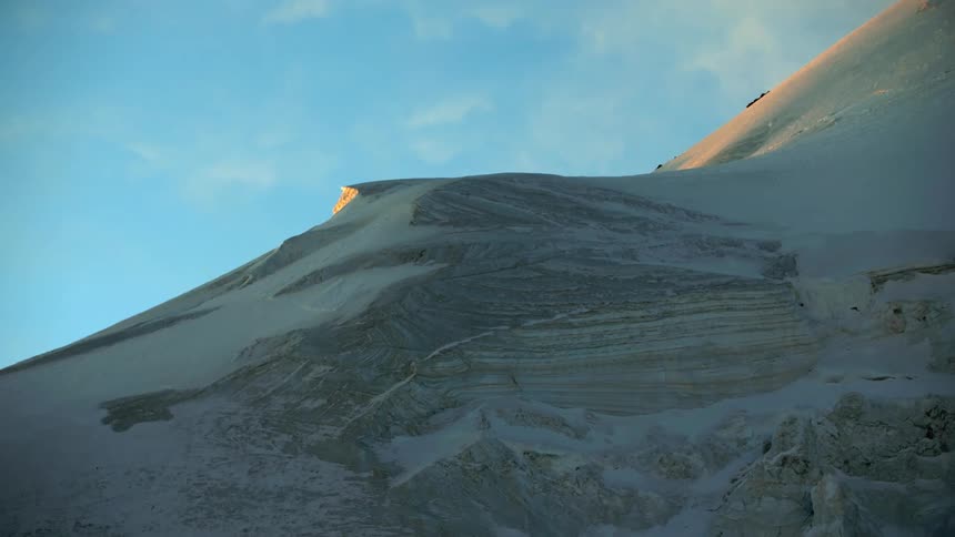A snow covered mountain slope under a blue sky